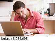 Мужчина средних лет хмурит брови во время работы за лэптопом. Стоковое фото, фотограф Monkey Business Images / Фотобанк Лори