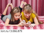 Две девочки подружки с телефонами лежат на кровати (2011 год). Редакционное фото, фотограф Игорь Низов / Фотобанк Лори