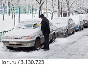 Автолюбитель счищает снег и лед с лобового стекла автомобиля (2012 год). Стоковое фото, фотограф Родион Власов / Фотобанк Лори
