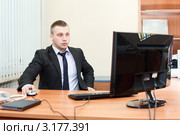 Мужчина за столом в офисе работает на компьютере. Стоковое фото, фотограф Кекяляйнен Андрей / Фотобанк Лори