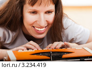 Улыбающаяся девушка печатает на старой печатной машинке, лежа на полу. Стоковое фото, фотограф Илья Андриянов / Фотобанк Лори
