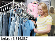 Женщина выбирает джинсы в магазине одежды. Стоковое фото, фотограф Дмитрий Калиновский / Фотобанк Лори