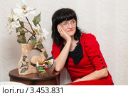 Красивая женщина в очках в красном платье сидит возле столика. Редакционное фото, фотограф Игорь Низов / Фотобанк Лори