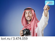 Молодой мужчина в арабской куфии с фотоаппаратом нажимает виртуальную кнопку. Стоковое фото, фотограф Elnur / Фотобанк Лори