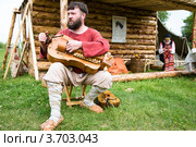 Историческая реконструкция. Мужчина поет древнерусские песни, играя на колесной лире на площадке фестиваля "Времена и эпохи" в Коломенском, Москва, Россия (2012 год). Редакционное фото, фотограф Николай Винокуров / Фотобанк Лори