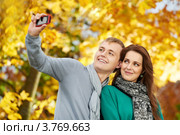 Парень и девушка фотографируют сами себя на мобильный телефон в осеннем парке. Стоковое фото, фотограф Дмитрий Калиновский / Фотобанк Лори