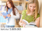 Красивая молодая девушка с книгами на фоне библиотеки. Стоковое фото, фотограф CandyBox Images / Фотобанк Лори