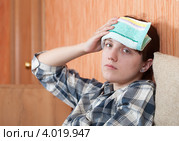 Девушка с компрессом и головной болью дома на диване. Стоковое фото, фотограф Яков Филимонов / Фотобанк Лори