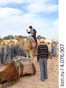 Экскурсовод показывает туристам как правильно сидеть на верблюде. Douz, Tunisia (2012 год). Редакционное фото, фотограф Кекяляйнен Андрей / Фотобанк Лори