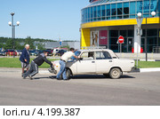Двое мужчин помогают пожилым людям убрать с дороги заглохнувший автомобиль (2012 год). Редакционное фото, фотограф Елена Коромыслова / Фотобанк Лори