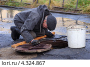 Сантехник над канализационным люком (2011 год). Редакционное фото, фотограф MerSavets / Фотобанк Лори