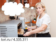 Пожилая домохозяйка готовит в микроволновке курицу в пакете. Стоковое фото, фотограф Кекяляйнен Андрей / Фотобанк Лори