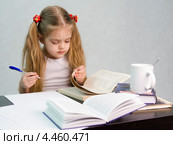 Девочка листает книгу и пишет на листе бумаги конспект сидя за столом. Стоковое фото, фотограф Иванов Алексей / Фотобанк Лори