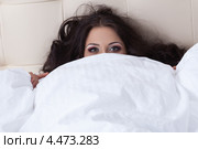 Красивая брюнетка лежит под белым одеялом, натянув его на себя до глаз. Стоковое фото, фотограф Гурьянов Андрей / Фотобанк Лори