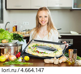 Счастливая домохозяйка готовит запеченную рыбу на кухне. Стоковое фото, фотограф Яков Филимонов / Фотобанк Лори