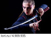 Воинственная женщина в японской одежде с катаной в руках на черном фоне. Стоковое фото, фотограф Elnur / Фотобанк Лори