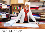 Продавец отмеряет кусок ткани в магазине. Стоковое фото, фотограф Яков Филимонов / Фотобанк Лори