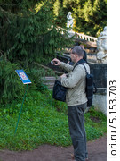 Турист сканирует QR-код в Нижнем парке Петергофа (2013 год). Редакционное фото, фотограф Геннадий Соловьев / Фотобанк Лори