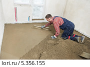 Рабочий выравнивает цементно-песчаную стяжку пола. Стоковое фото, фотограф Дмитрий Калиновский / Фотобанк Лори