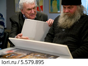 Фотограф РИА "Новости" Юрий Кавер показывает свои фотографии Иеромонаху Савватию на круглом столе, посвященном православной фотографии, в "Фотоцентре" на Гоголевском бульваре (2014 год). Редакционное фото, фотограф Николай Винокуров / Фотобанк Лори
