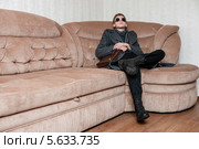 Парень в берцах и пальто сидит на диване. Стоковое фото, фотограф Игорь Низов / Фотобанк Лори