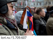 Мужчина держит православный крест и российский триколор на митинге "В поддержку Крыма и против фашизма" на площади Революции города Москвы 15 марта 2014. Редакционное фото, фотограф Николай Винокуров / Фотобанк Лори