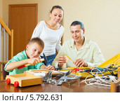 Родители вместе с мальчиком-подростком что-то моделируют с помощью инструментов дома. Стоковое фото, фотограф Яков Филимонов / Фотобанк Лори