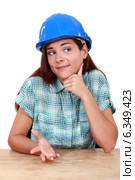 Thoughtful woman in a hardhat sitting at a desk. Стоковое фото, фотограф Phovoir Images / Фотобанк Лори