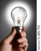 Mans hand holding a light bulb against grey background. Стоковое фото, агентство Ingram Publishing / Фотобанк Лори