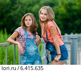 Две красивые девушки в джинсовых шортах стоят возле железного забора. Стоковое фото, фотограф Игорь Низов / Фотобанк Лори
