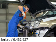Женщина-сборщик крепит деталь в подкапотном пространстве автомобиля. Автомобильный завод (2014 год). Редакционное фото, фотограф Ирина Борсученко / Фотобанк Лори