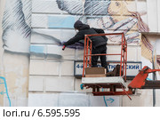 Человек наносит рисунок баллончиком на фасад здания (2014 год). Редакционное фото, фотограф Родион Власов / Фотобанк Лори