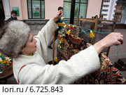 Девушка вешает старую советскую гирлянду на ширму с советским ковром в импровизированной коммунальной квартире на улице Старый Арбат в центре Москвы (2013 год). Редакционное фото, фотограф Николай Винокуров / Фотобанк Лори