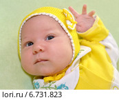 Портрет грудного ребенка в желтом чепчике на зеленом фоне. Стоковое фото, фотограф Ирина Борсученко / Фотобанк Лори