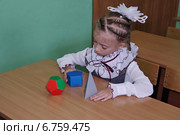 Девочка в классе занимается с геометрическими фигурами, сидя за партой. Стоковое фото, фотограф Илюхина Наталья / Фотобанк Лори