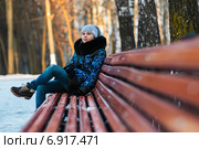 Мечтающая юная девушка сидит на лавочке зимой в парке. Стоковое фото, фотограф Игорь Низов / Фотобанк Лори
