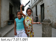 Two little black Arab girl standing on a narrow street. Стоун Таун - Каменный город на острове Занзибар, две десятилетние девочки  гримасничают и кривляются перед туристами с фотокамерами. (2008 год). Редакционное фото, фотограф Владимир Григорьев / Фотобанк Лори