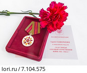 Юбилейная медаль «70 лет Победы в Великой Отечественной войне 1941—1945 гг.» с удостоверением и красная гвоздика. Награда ветерану. Стоковое фото, фотограф Владимир Сергеев / Фотобанк Лори