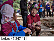 Asian woman with rose hairstyle smiles on rural holiday, China. Женщина народности мяо с улыбкой на лице и розой в прическе, держит в руках комок отварного риса, это угощение для гостей сельского праздника в деревне Ланде, Гуйчжоу, Китай. (2010 год). Редакционное фото, фотограф Владимир Григорьев / Фотобанк Лори