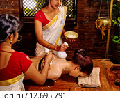 Woman having massage with pouch of rice. Стоковое фото, фотограф Gennadiy Poznyakov / Фотобанк Лори
