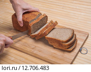 Резка буханки черного хлеба на разделочной доске. Стоковое фото, фотограф Алёшина Оксана / Фотобанк Лори