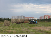 Трактор убирает сено на фоне города Шатуры (2015 год). Редакционное фото, фотограф Дмитрий Неумоин / Фотобанк Лори