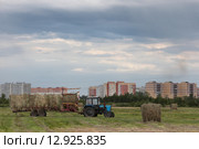 Тракторист убирает сено на фоне города Шатуры (2015 год). Редакционное фото, фотограф Дмитрий Неумоин / Фотобанк Лори