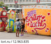 Надпись "Berlin lacht"  и разговаривающие девушки летним днем на Александрплатц в Берлине (2015 год). Редакционное фото, фотограф Наталья Николаева / Фотобанк Лори