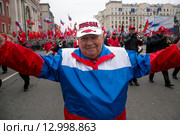 Мужчина ы одежде цветов российского триколора идет во главе оркестра в рамках акции "Мы едины!" в российский праздник День народного единства на Тверской улице в городе Москве, Россия 4 ноября 2015. Редакционное фото, фотограф Николай Винокуров / Фотобанк Лори