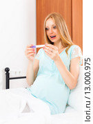 Suprised pregnant woman with pregnancy test at home interior. Стоковое фото, фотограф Яков Филимонов / Фотобанк Лори
