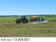 Трактор John Deere с прицепным опрыскивателем работает на поле (2015 год). Редакционное фото, фотограф Михаил Рудницкий / Фотобанк Лори
