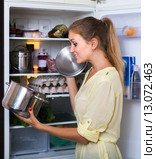 Hungry female standing near fridge with pan of food. Стоковое фото, фотограф Яков Филимонов / Фотобанк Лори