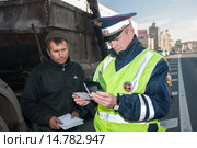 Сотрудник ДПС проверяет документы у водителя грузового автомобиля на городской улице (2013 год). Редакционное фото, фотограф Михаил Михин / Фотобанк Лори