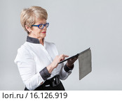 Пожилая женщина нажимает на тачскрин планшета, серый фон. Стоковое фото, фотограф Кекяляйнен Андрей / Фотобанк Лори